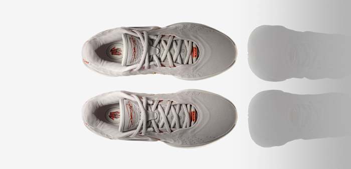 Side view of LeBron James' white and orange Nike basketball shoes.